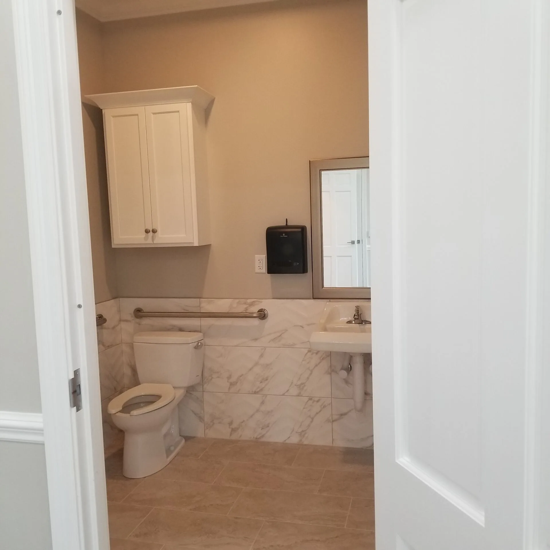 ADA restroom with pedestal sink, marble wainscoting, and grab bar